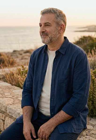 Hombre sentado junto al mar al atardecer